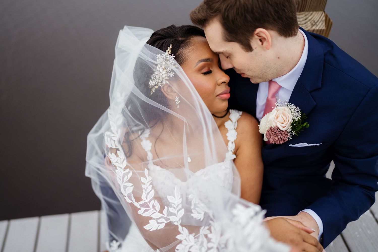 Romantic wedding couple shares intimate moments in elegant formal attire with delicate lace veil details.