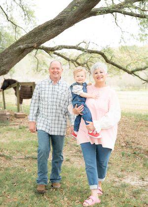 A couple in casual attire shares joyful moments together outdoors under a large tree.