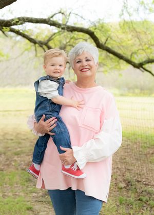 A pair in matching pink tops share joyful moments together outdoors under blooming spring trees.