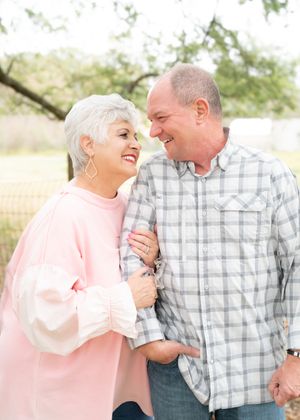 A couple wearing pink and plaid share intimate laughing moments in an outdoor setting.