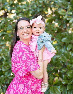 Mother and baby share joyful moments together in an outdoor garden setting with soft bokeh lighting.