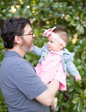 A sweet moment shared between parent and child against green foliage outdoors.