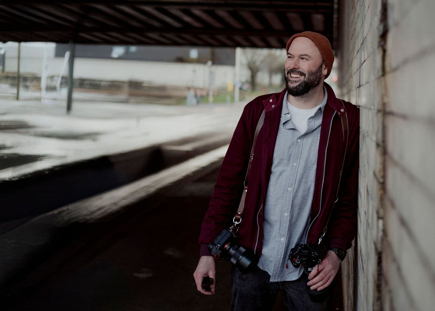 Casual portrait of Paul Mavor in burgundy jacket smiling against industrial background shot by David Donaldson Photography.