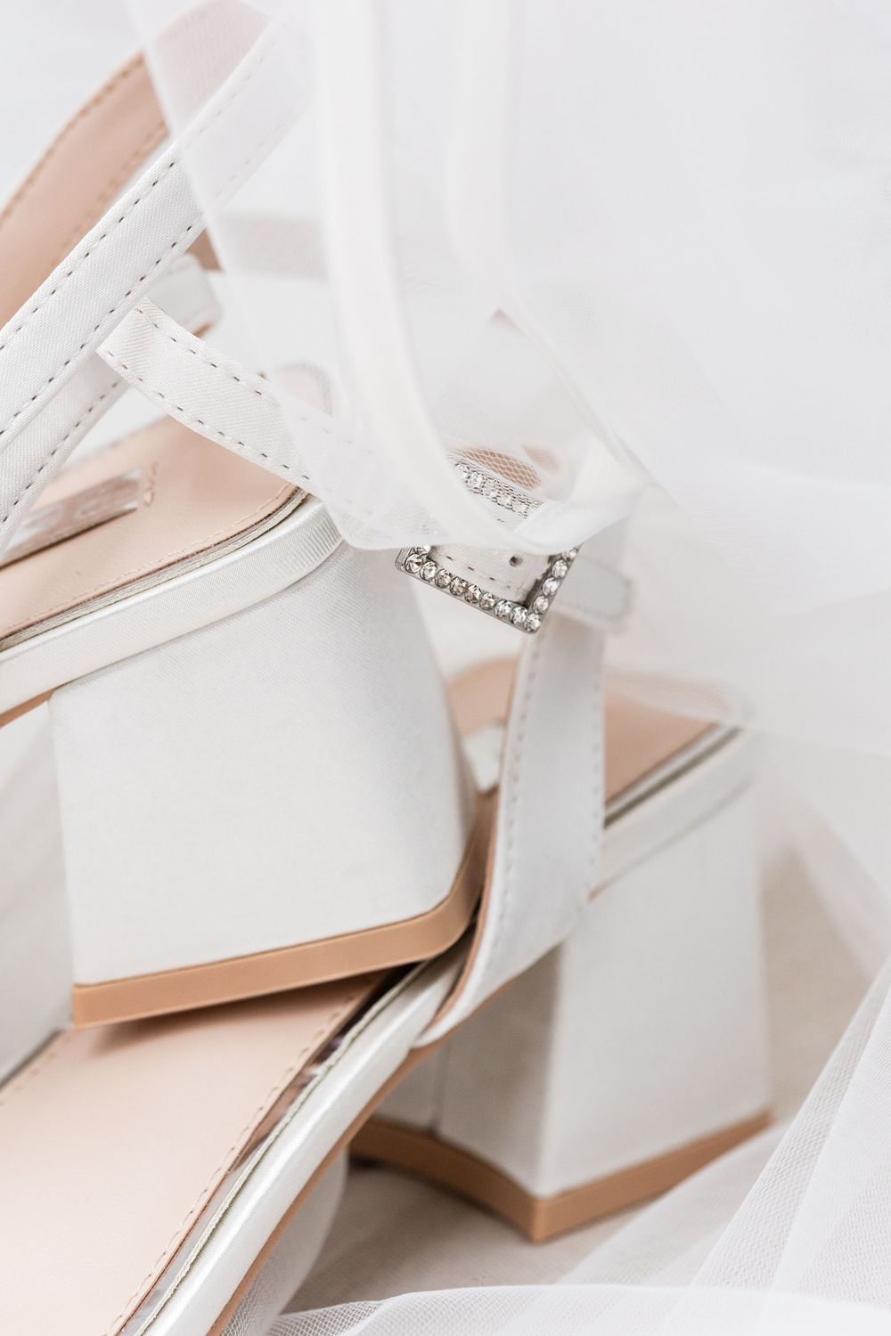 White satin bridal shoes with delicate bow details arranged in an artistic composition.