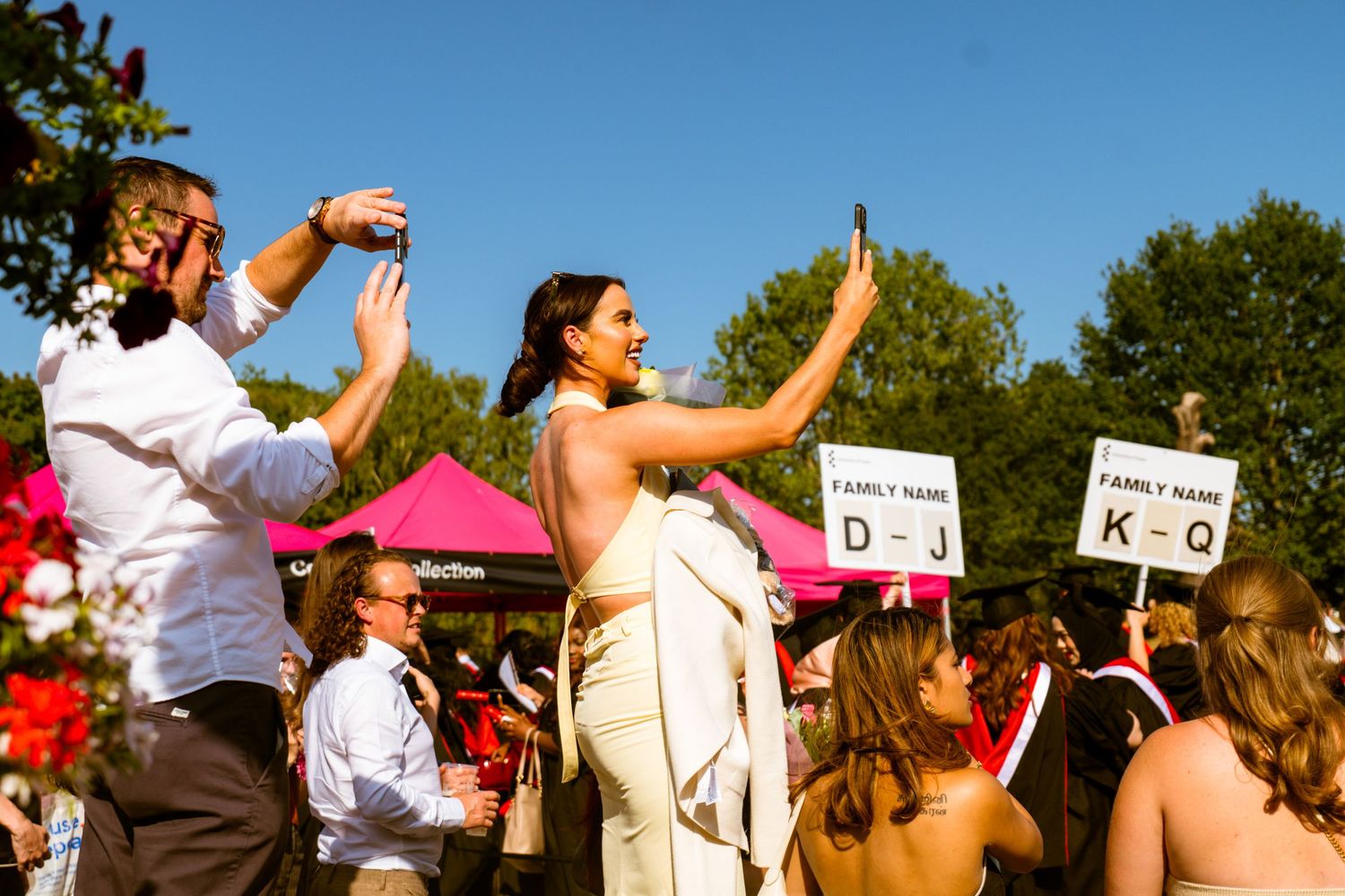 A group of people stand in a line outdoors raising their hands in a synchronized dance or performance motion.