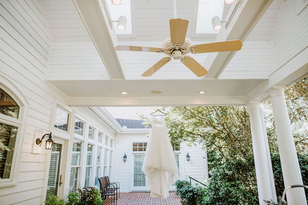 A bright white covered porch with ceiling fans and columns showcases elegant coastal architecture details.