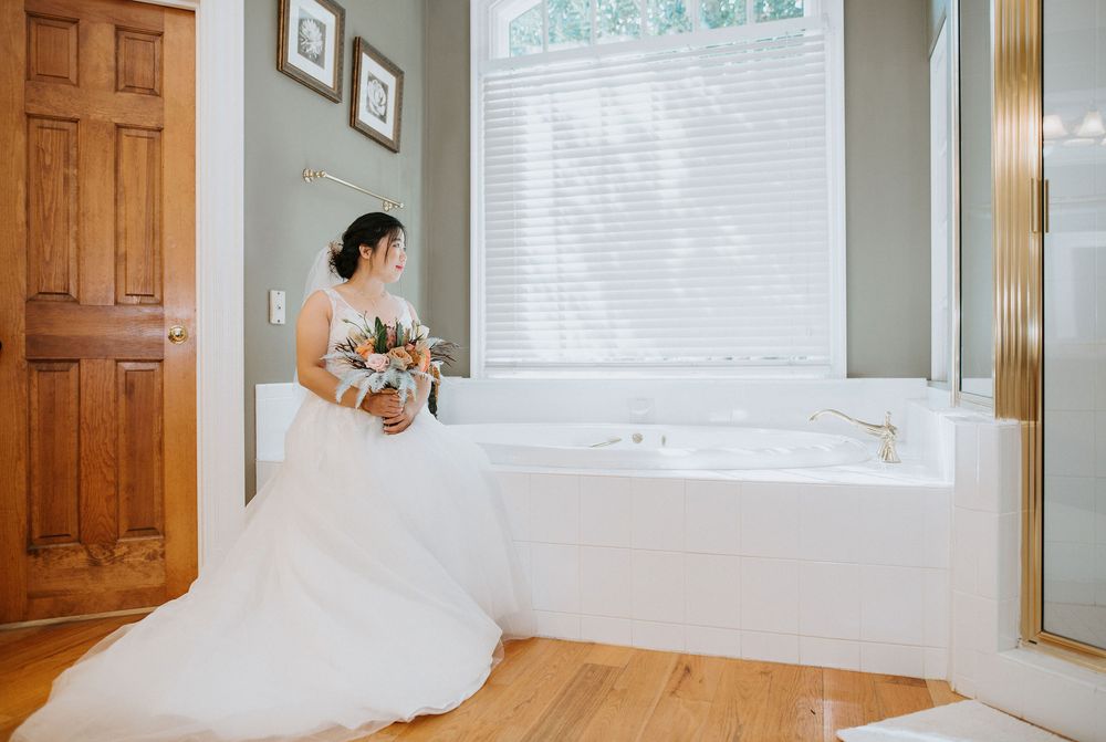 A flowing white wedding dress twirls gracefully in a sunlit room with wooden doors and hardwood floors.
