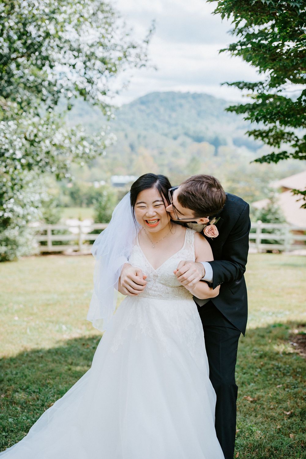 A romantic wedding moment captured outdoors with mountains in the background on a sunny spring day.