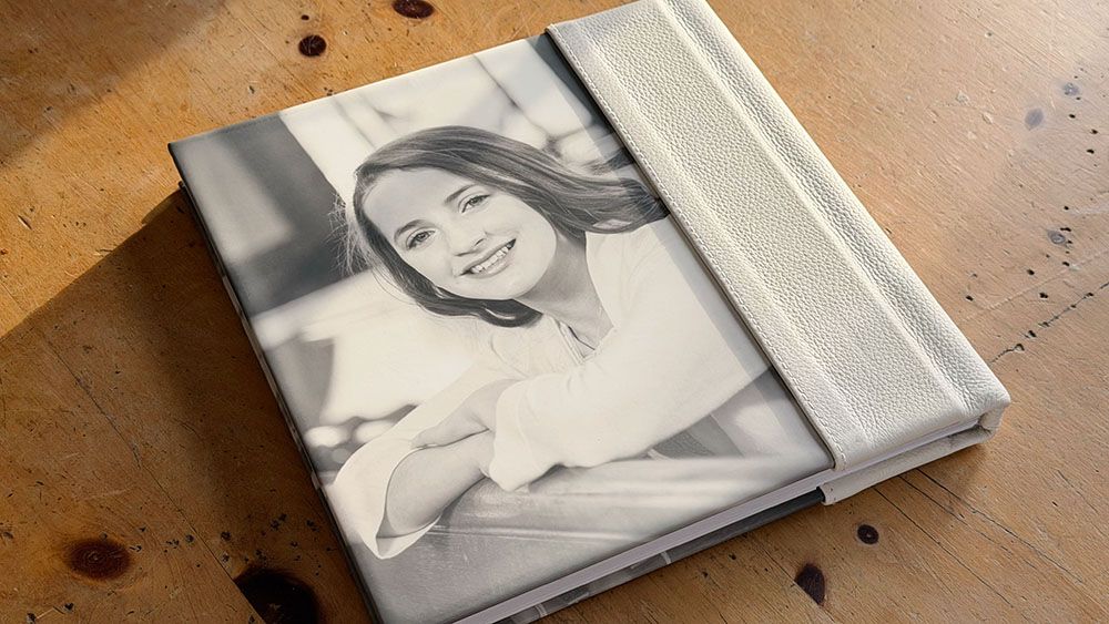 A series of black and white portrait photographs arranged on a wooden surface.