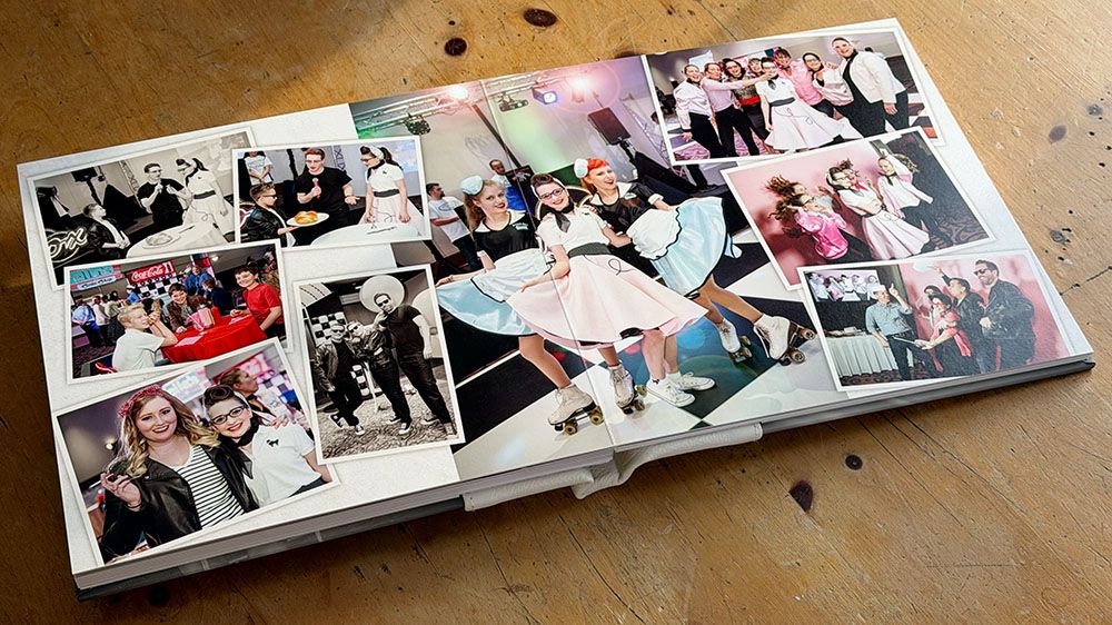 Several vintage photo albums laid out in a row on a wooden surface with photos visible inside them.