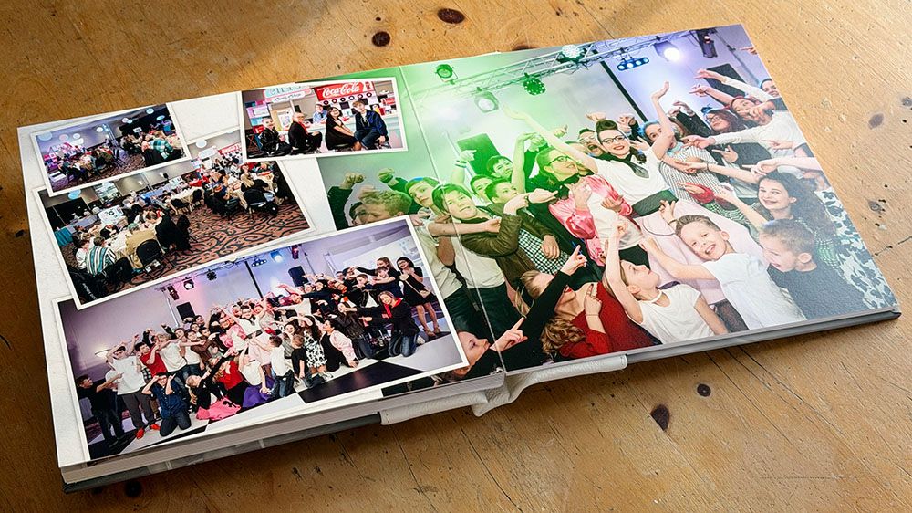 A collection of photo albums or scrapbooks laid out in a row on a wooden surface with scattered decorative elements.