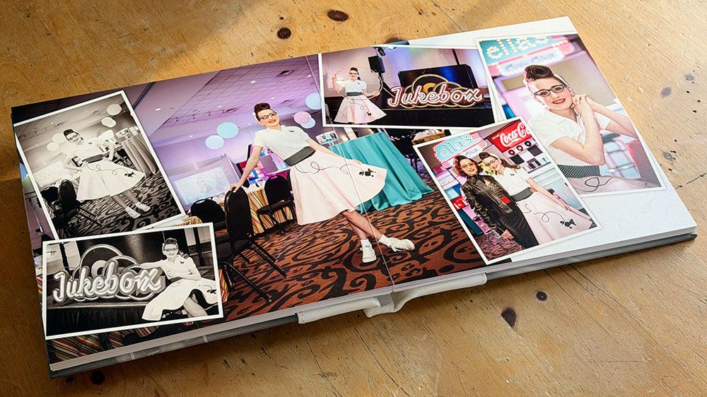 A row of photo albums or wedding books laid out on a wooden surface showing various photography spreads.