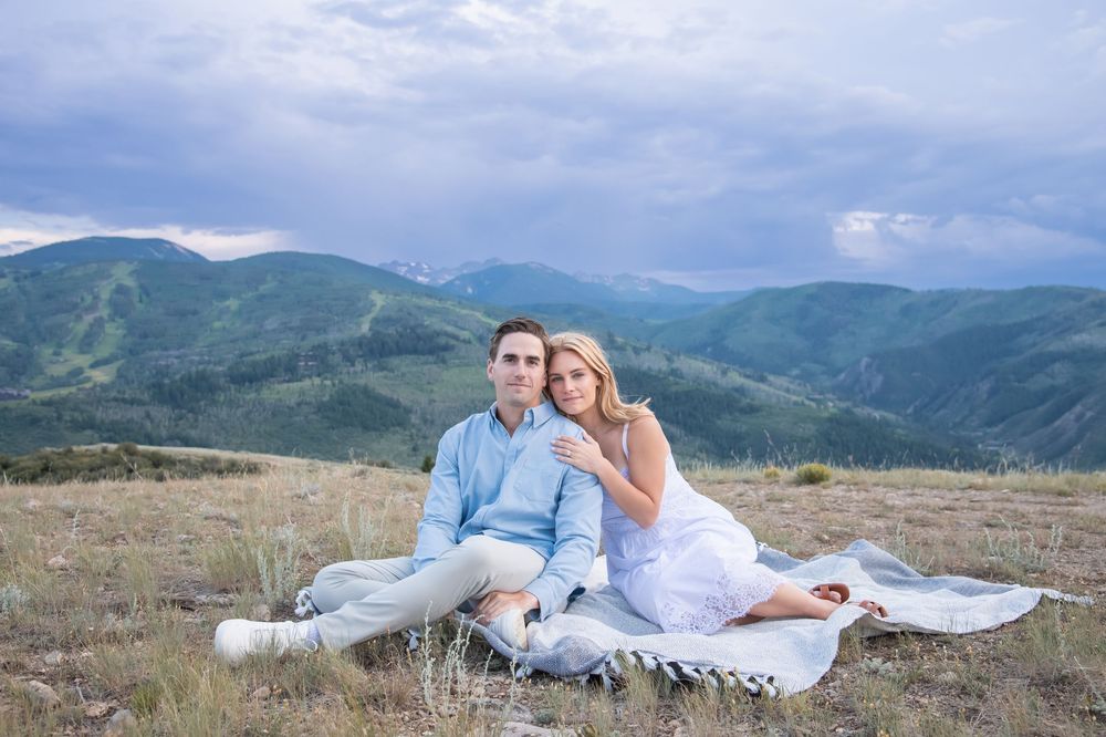 A wedding couple poses for romantic mountain photos in a scenic outdoor setting during sunset.