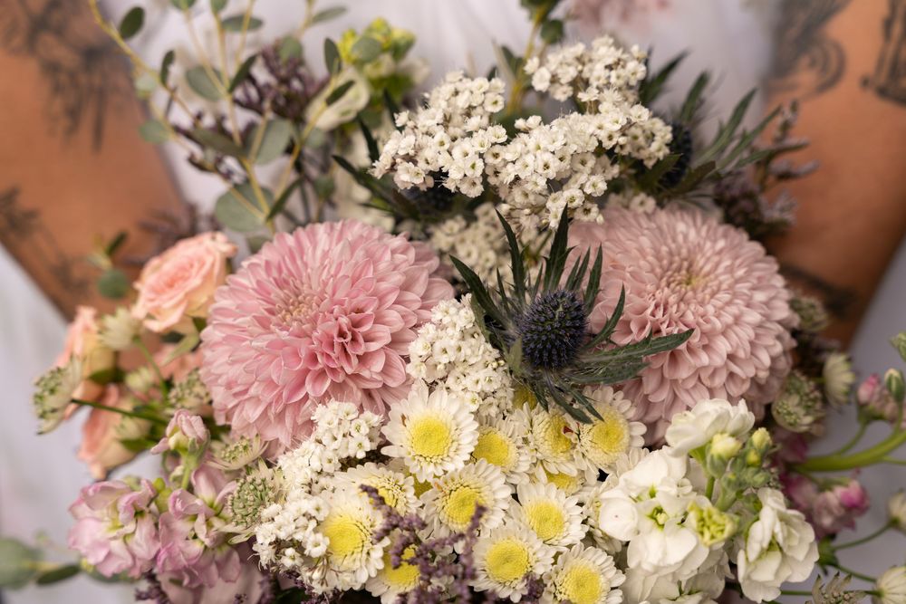 A delicate bouquet featuring pink chrysanthemums, white baby's breath, and small yellow daisies in a soft arrangement.