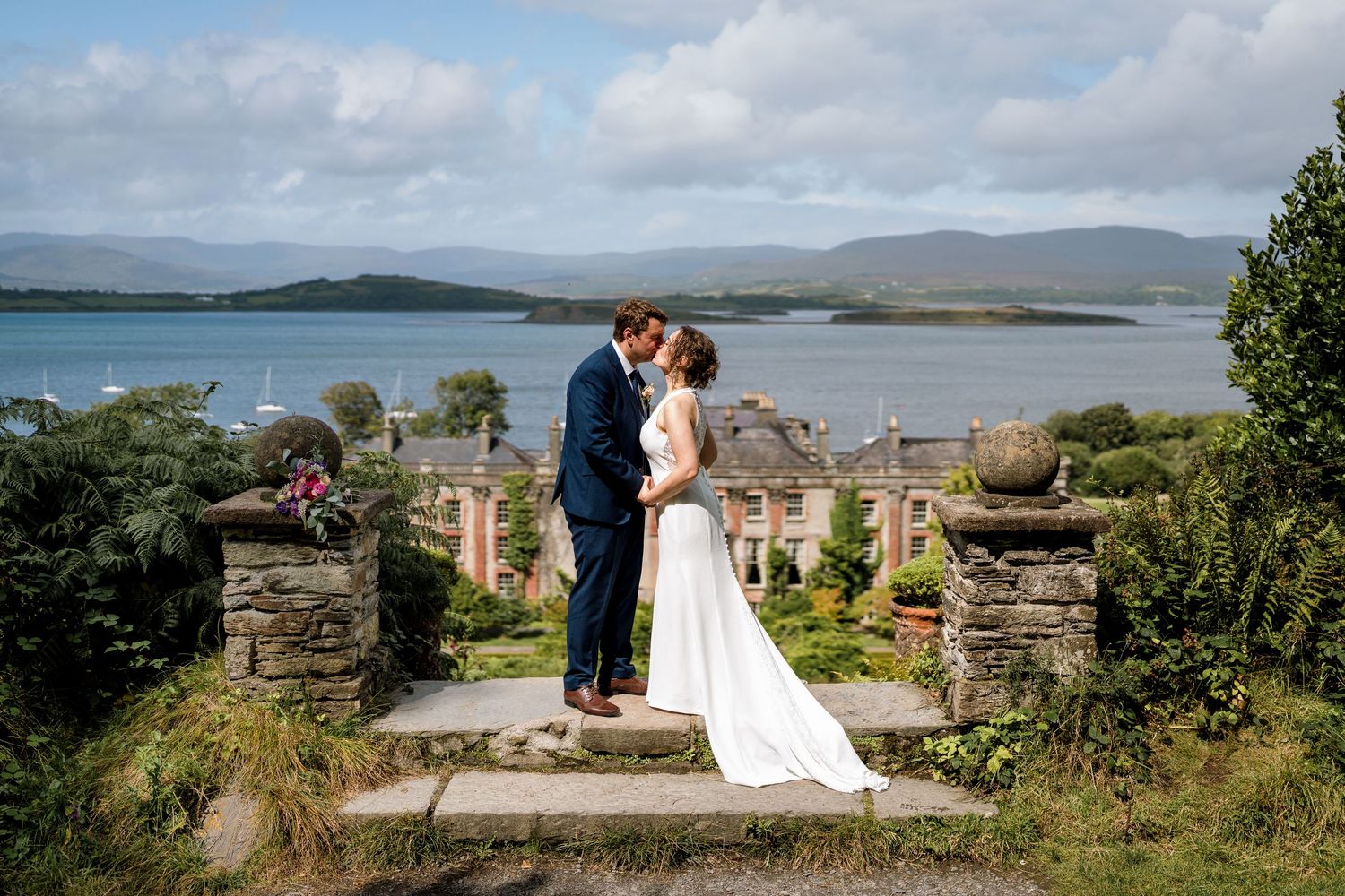 A couple shares a romantic moment at a scenic coastal overlooking Bantry House - Bantry House wedding photos by Sarah Kate Photography