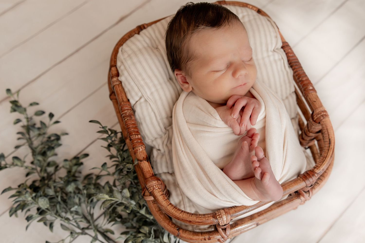 Wrapped newborn baby smiling while holding a small teddy bear plushie, photographed during a newborn session in Central Indiana