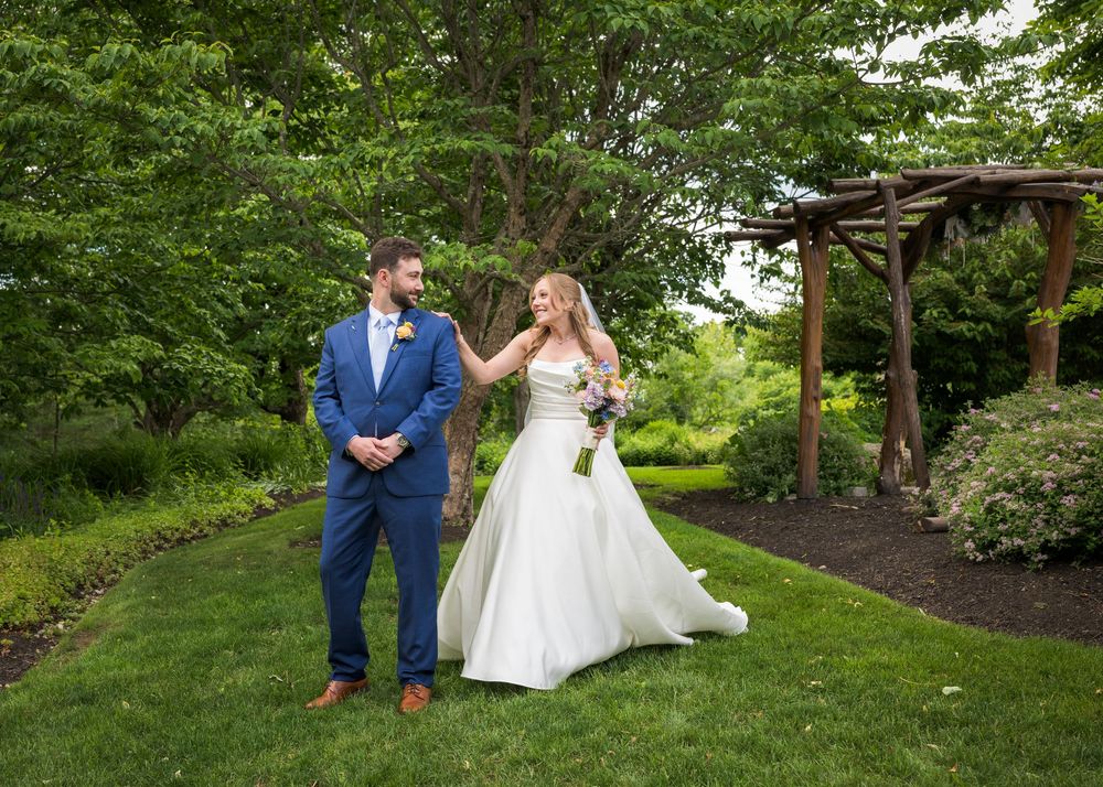 Bride and groom sharing a first look moment in a beautiful garden with lush green trees.