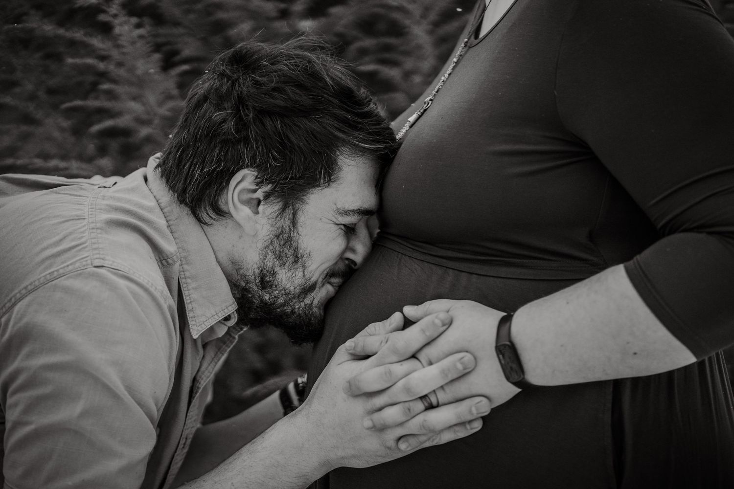 A tender black and white photo showing an intimate moment between a couple during a pregnancy photoshoot.