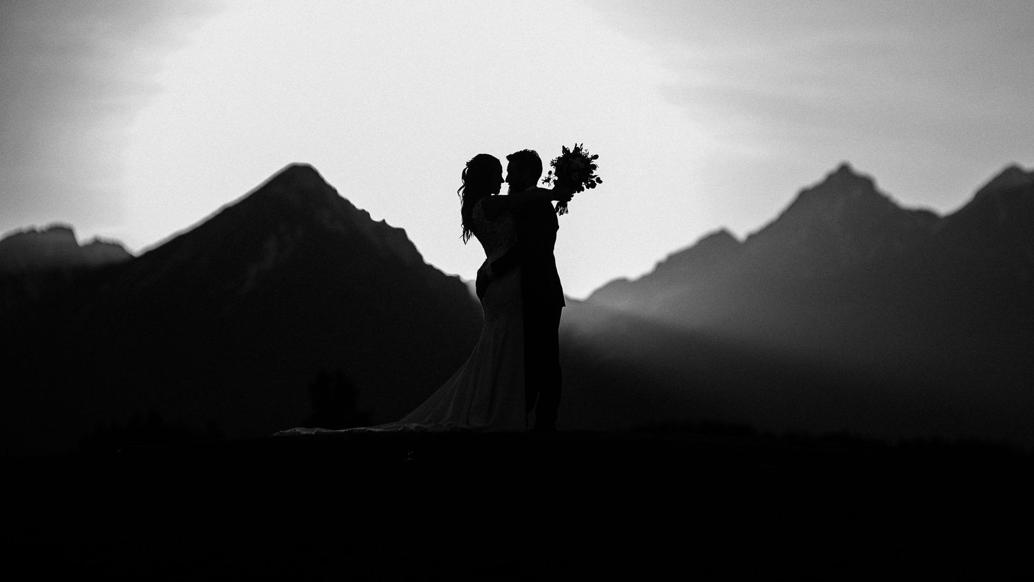 Nevesta a ženích v objatí na lúke s výhľadom na Tatry pri západe slnka