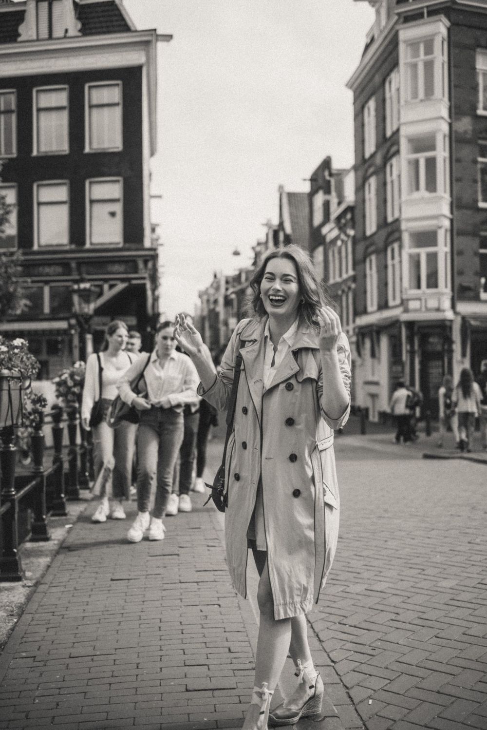 Black and white sequence of person walking and posing on cobblestone street in urban setting.