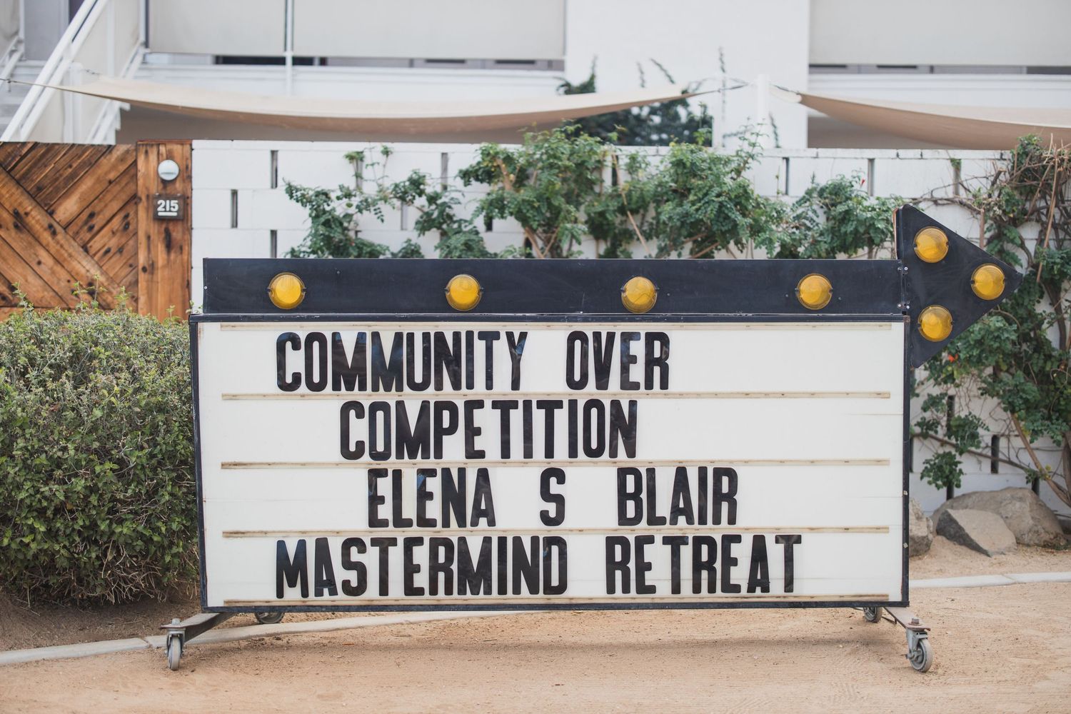 Sign reading Community Over Competition on white board outside building.