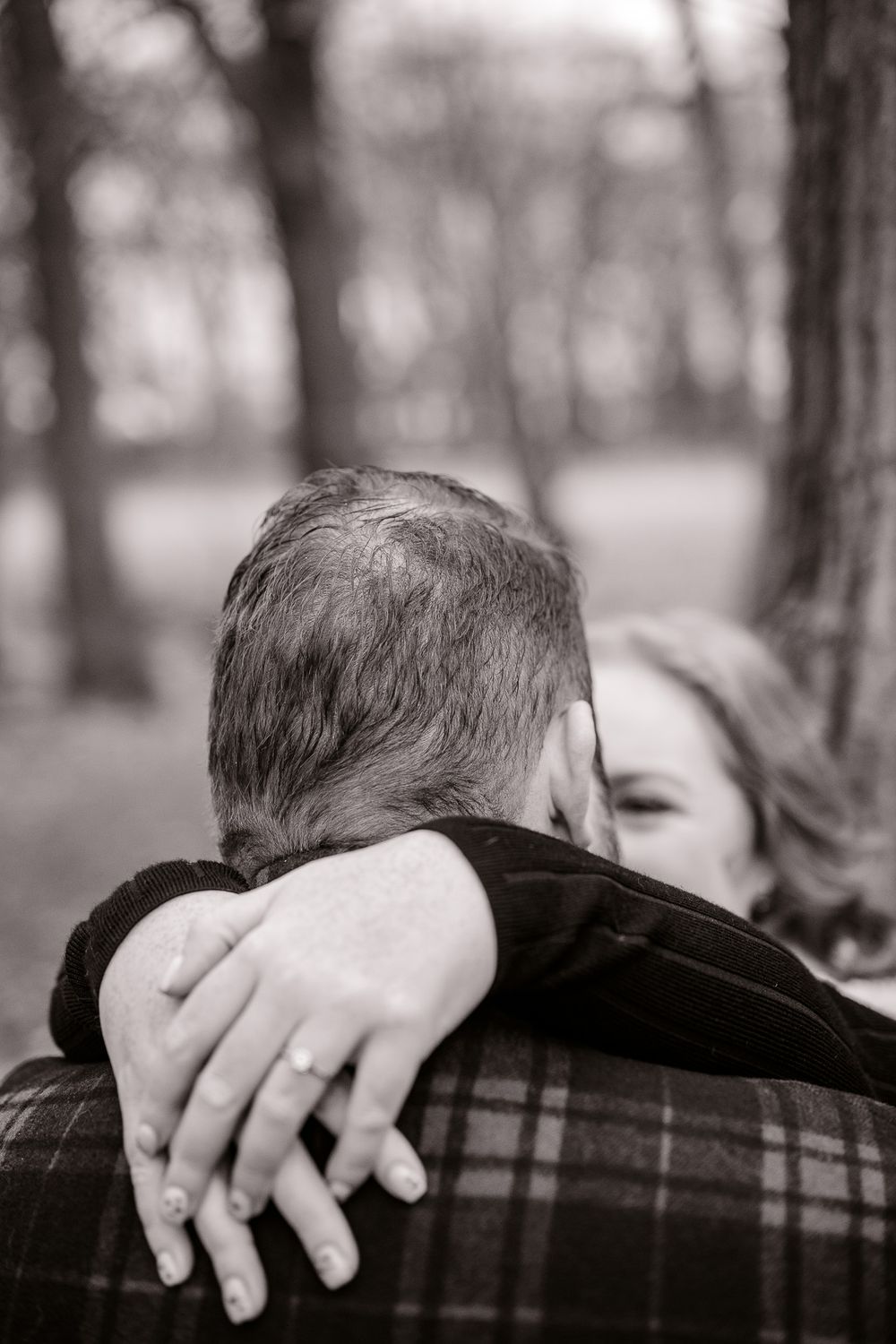 An intimate black and white photo showing a couple embracing with focus on their hands.