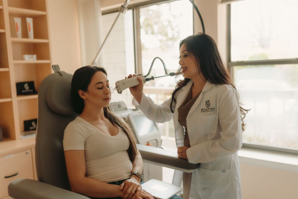 Healthcare professional in white coat examining patient in medical office chair during consultation appointment.