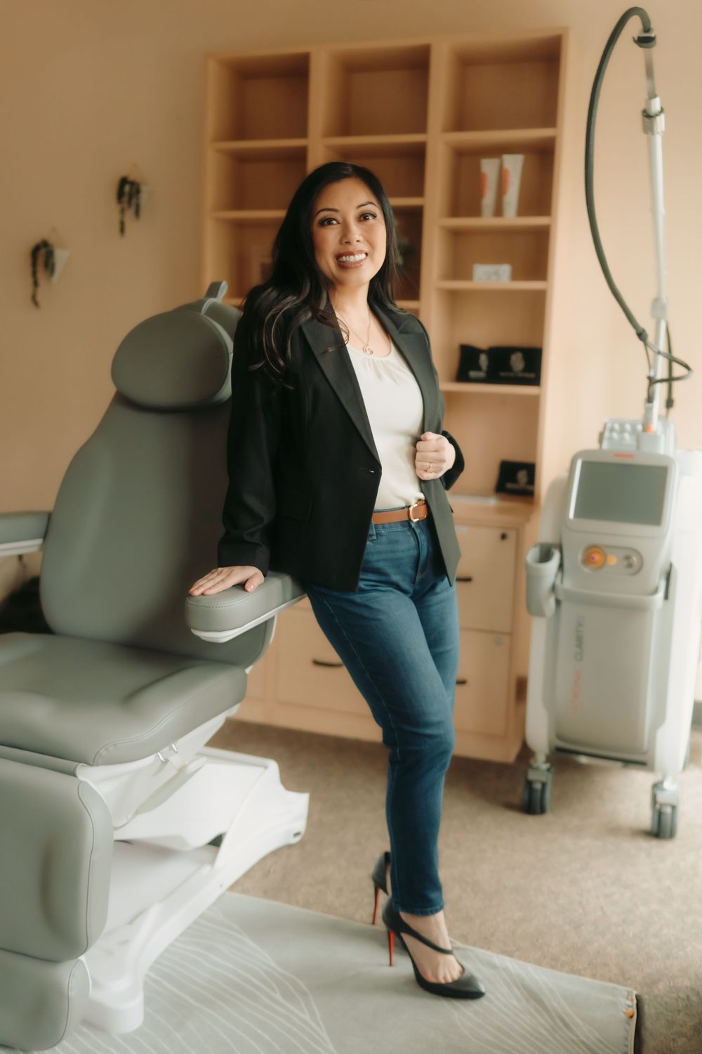 Professional medical office interior with examination chair, storage shelves, and modern equipment in warm beige tones.