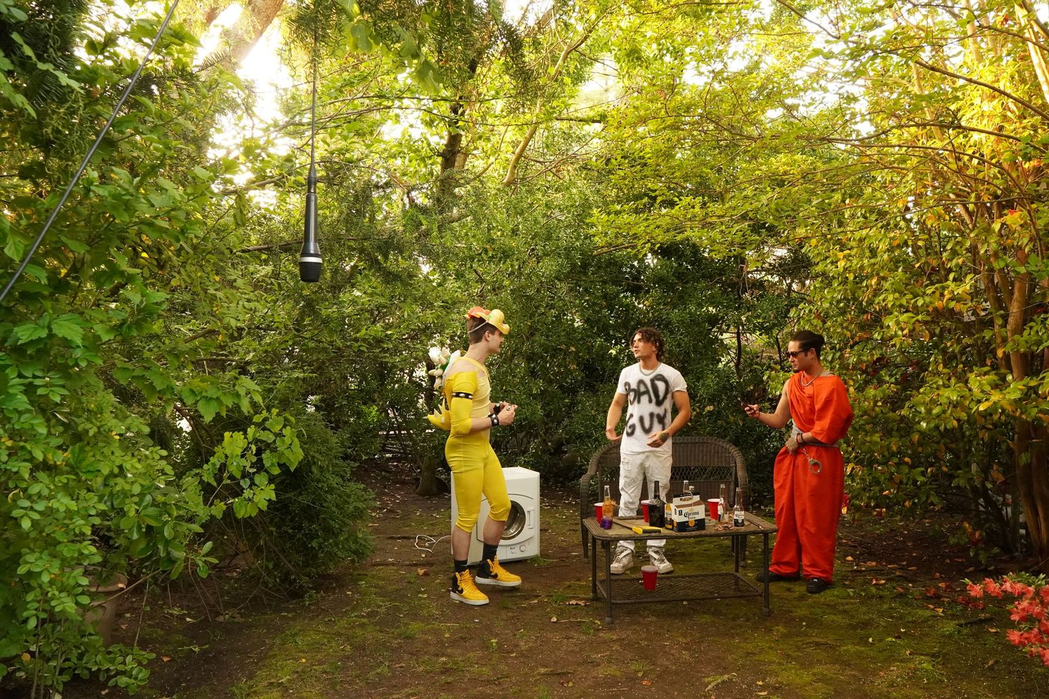 People in colorful outfits gather around a cart on a wooded path during a sunny afternoon.