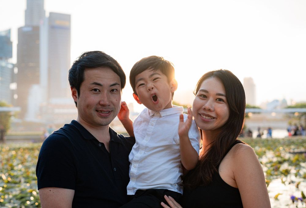 Family sharing joyful moment together outdoors with city backdrop at sunset.