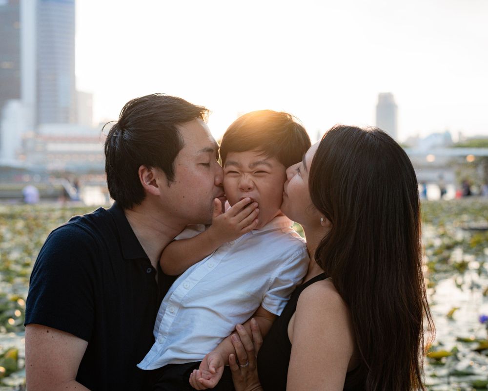 A joyful family moment captured outdoors during golden hour with skyscrapers in the background.