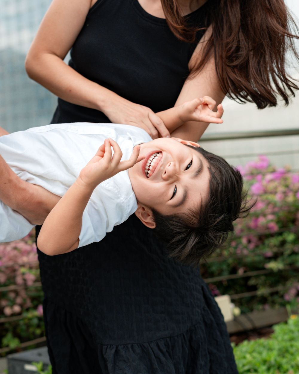 Playful moment of family fun against urban backdrop with flowering plants.