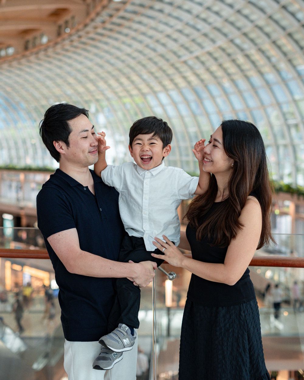 Happy family moment captured inside modern shopping mall with curved architectural ceiling.