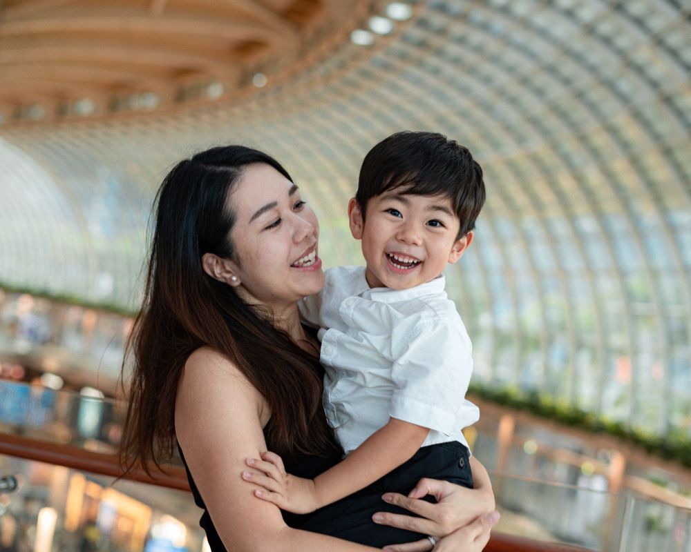 Joyful embrace between parent and child inside modern shopping mall.