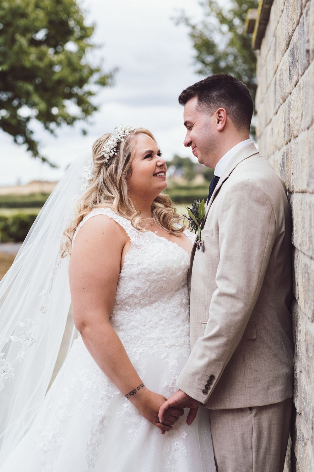 Newlywed couple shares intimate moments in a series of romantic outdoor wedding portraits against a stone wall.