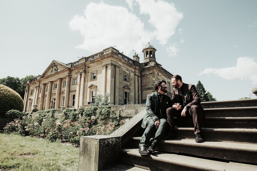 Wedding couple relaxes on outdoor stone steps of a historic building on a sunny day.