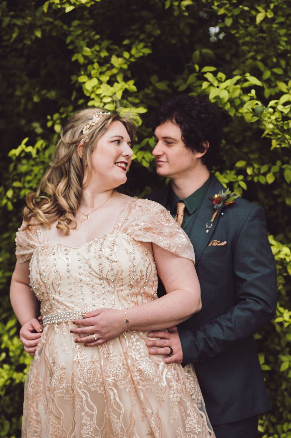 A couple in formal attire share tender moments against a leafy green backdrop in a sequence of romantic poses.