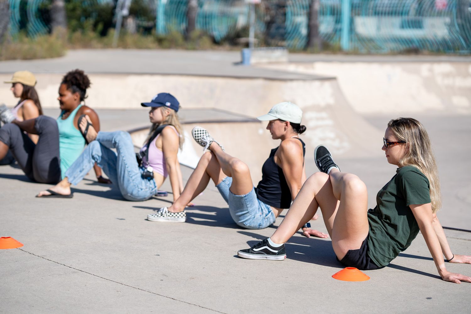 A diverse group of skaters do warm up stretches at the skatepark