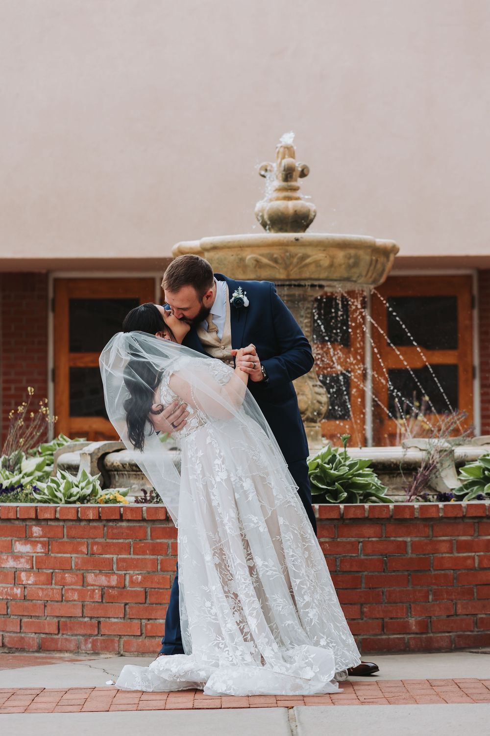 A sequence of photos showing a bride in a white wedding dress being helped up from a brick ledge during a wedding photoshoot.