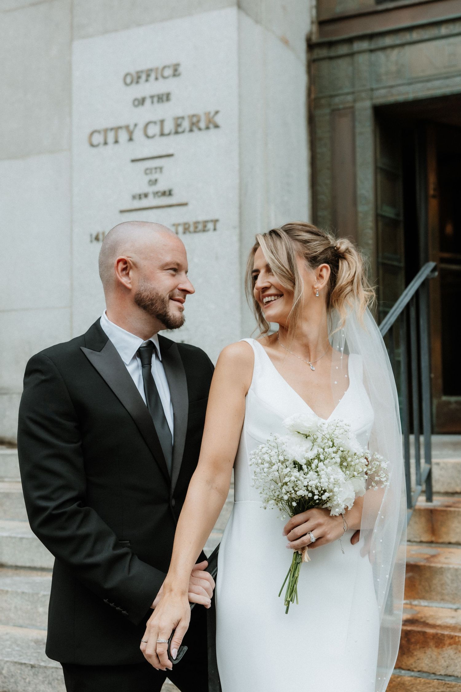 A bride and groom share intimate moments outside a city clerk's office in a series of candid wedding photos.