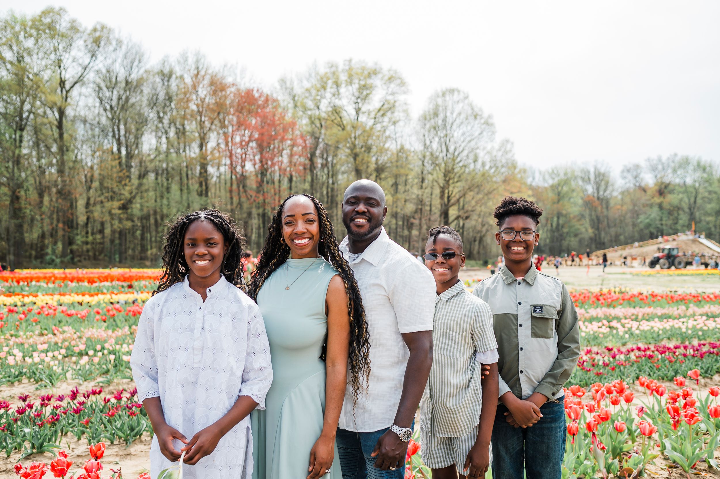Group photo in a beautiful tulip garden with rows of red and yellow flowers stretching into the distance.