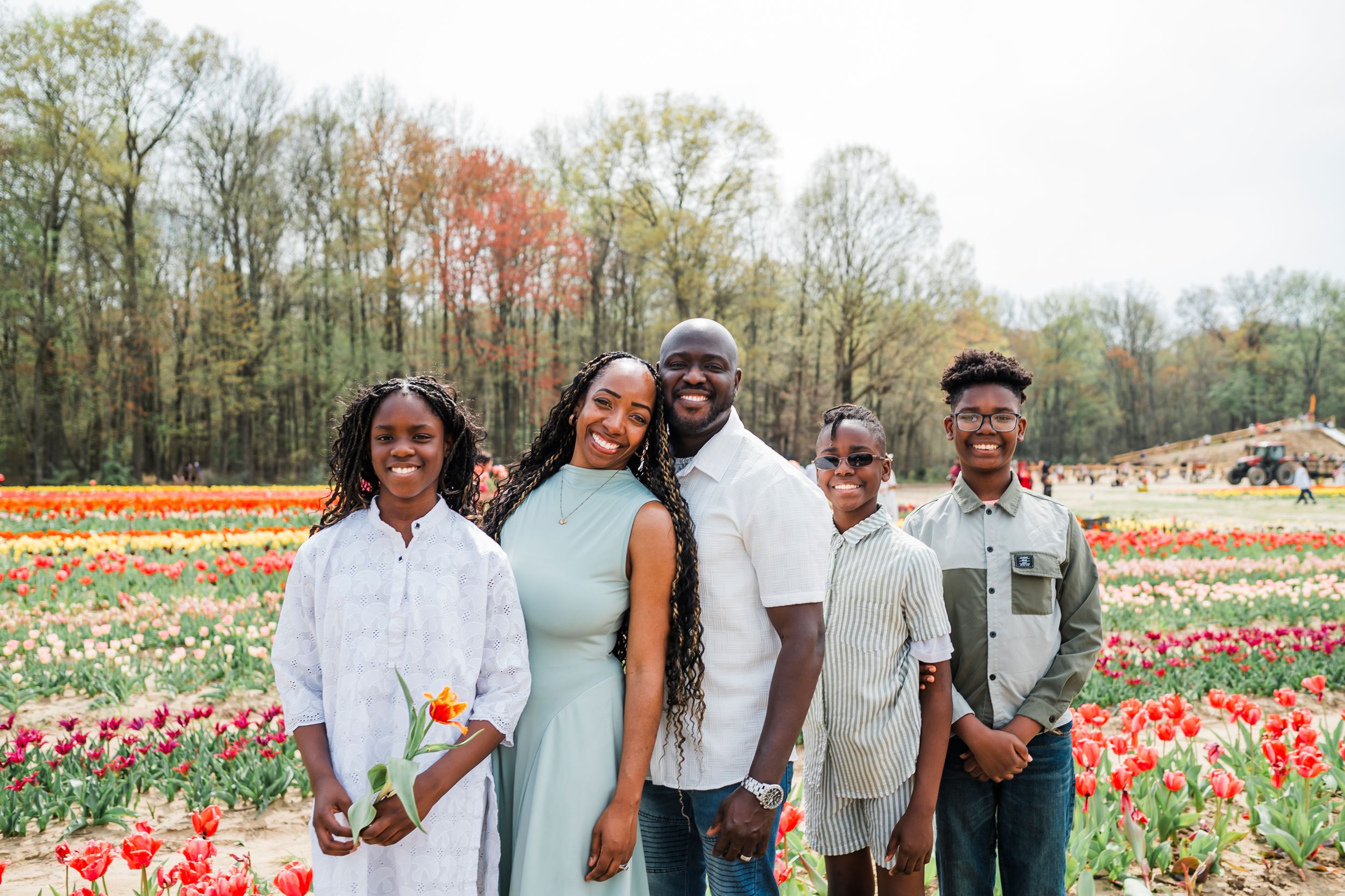 A group standing together in a vibrant tulip field with red and yellow flowers blooming under overcast skies.