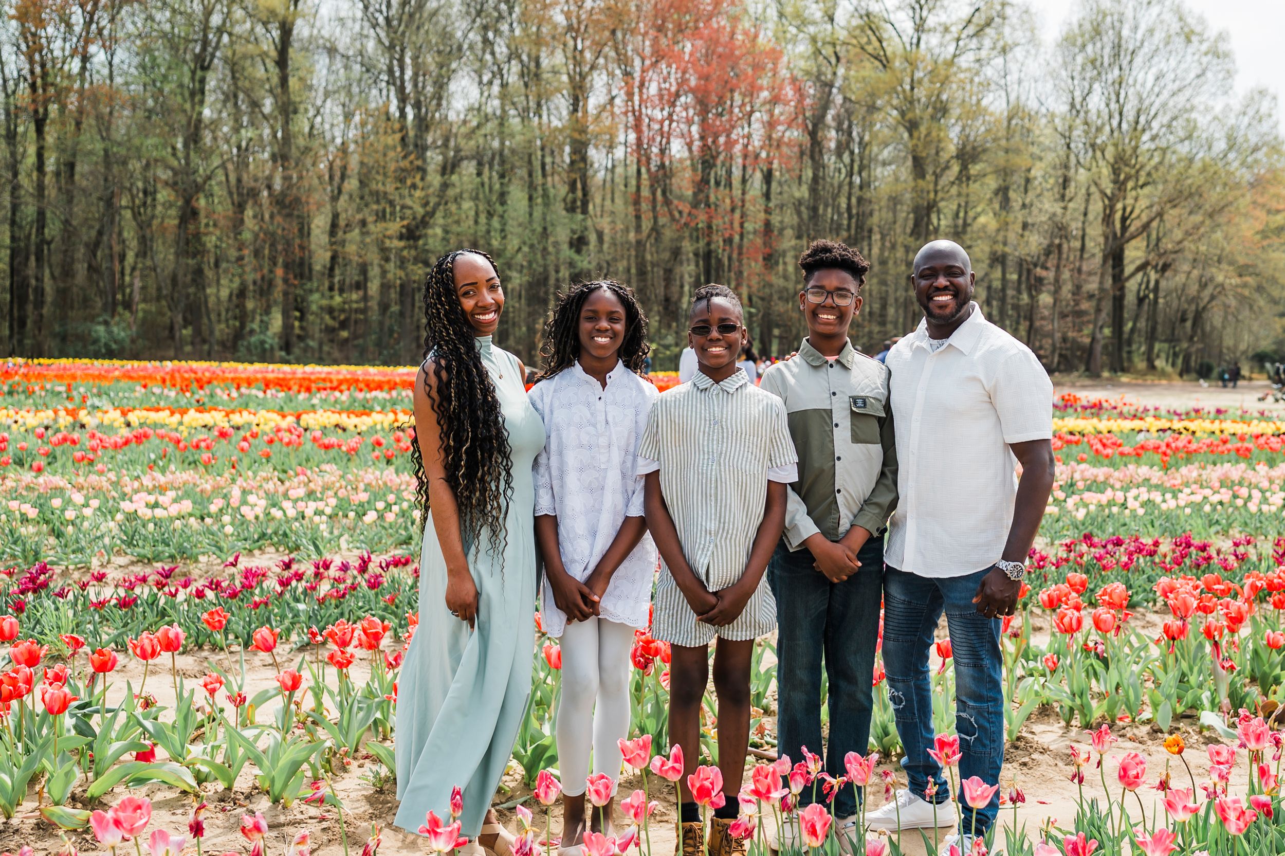 A group portrait taken in a colorful spring tulip garden with trees in the background.