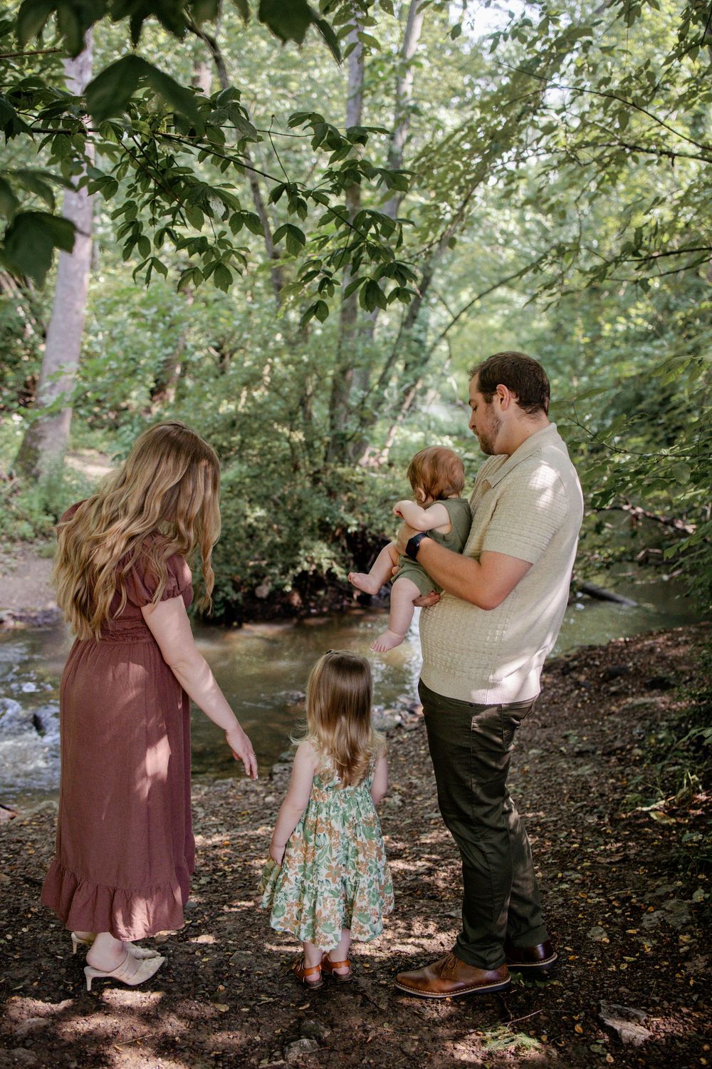 Group stands together by a peaceful creek in a lush green forest on a summer afternoon.