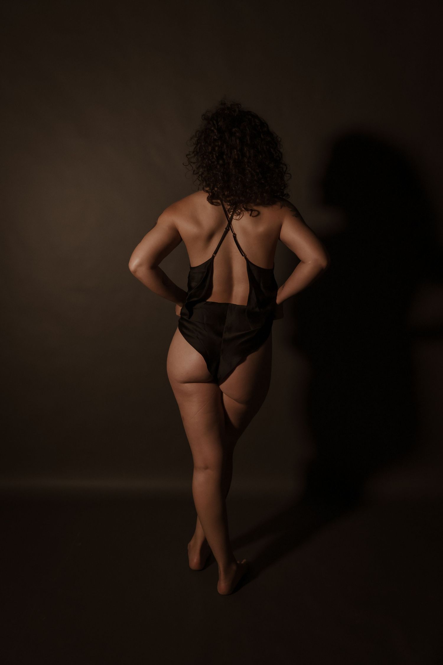 Artistic black and white boudoir photo with dramatic shadows.