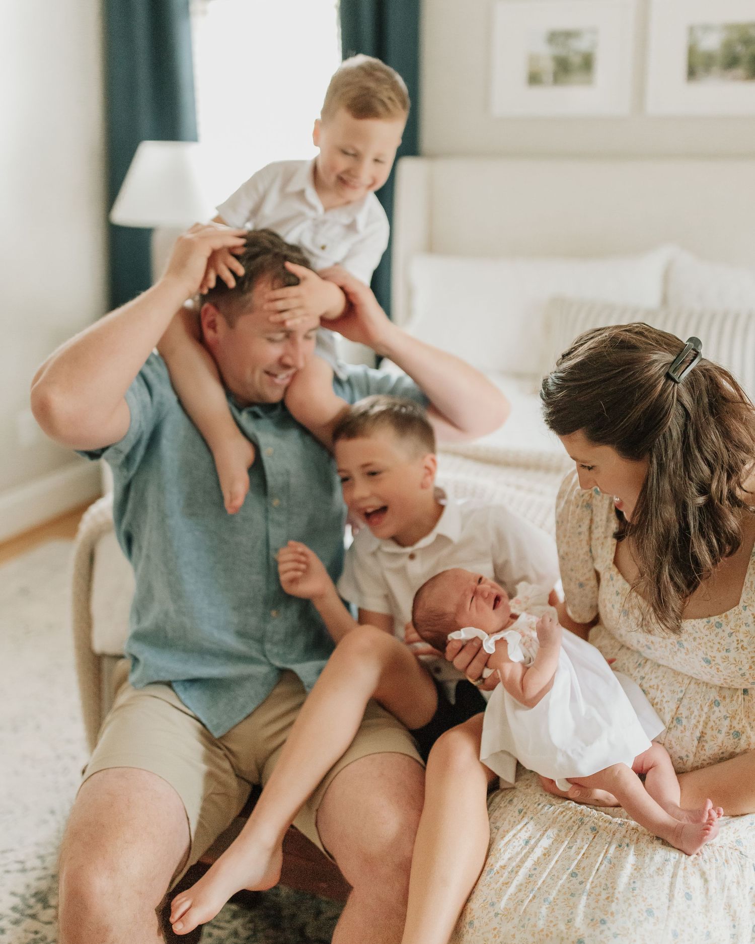 A family shares joyful moments together on a cozy couch with their newborn baby.