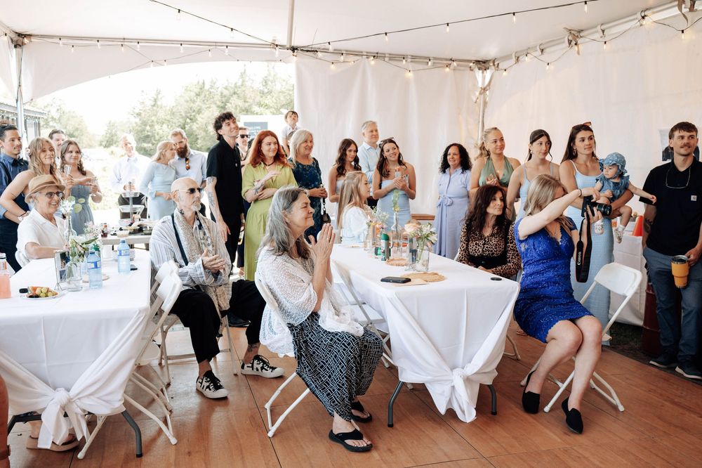 Wedding guests gathered under string lights at an outdoor reception celebration.