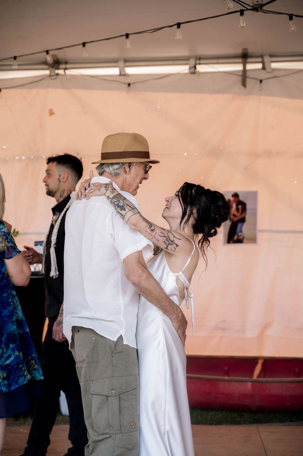 Wedding party dancing and having fun in an indoor venue with white walls and lighting.