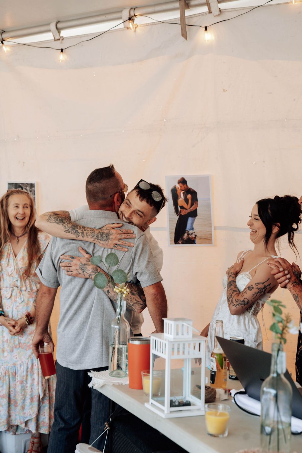 Candid moments at wedding reception showing guests enjoying toasts under white tent with decorative lanterns.