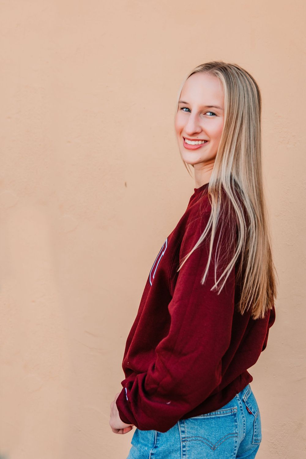 Outdoor senior portrait of teen girl in natural light with stylish outfit and soft smile.